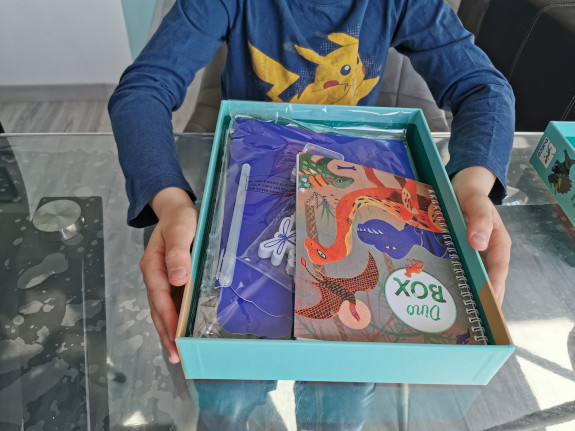 enfant présentant les pièces du coffret d'activités "Le monde des dinosaures"