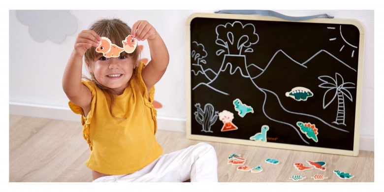 petite fille qui écrit sur un tableau noir magnétique